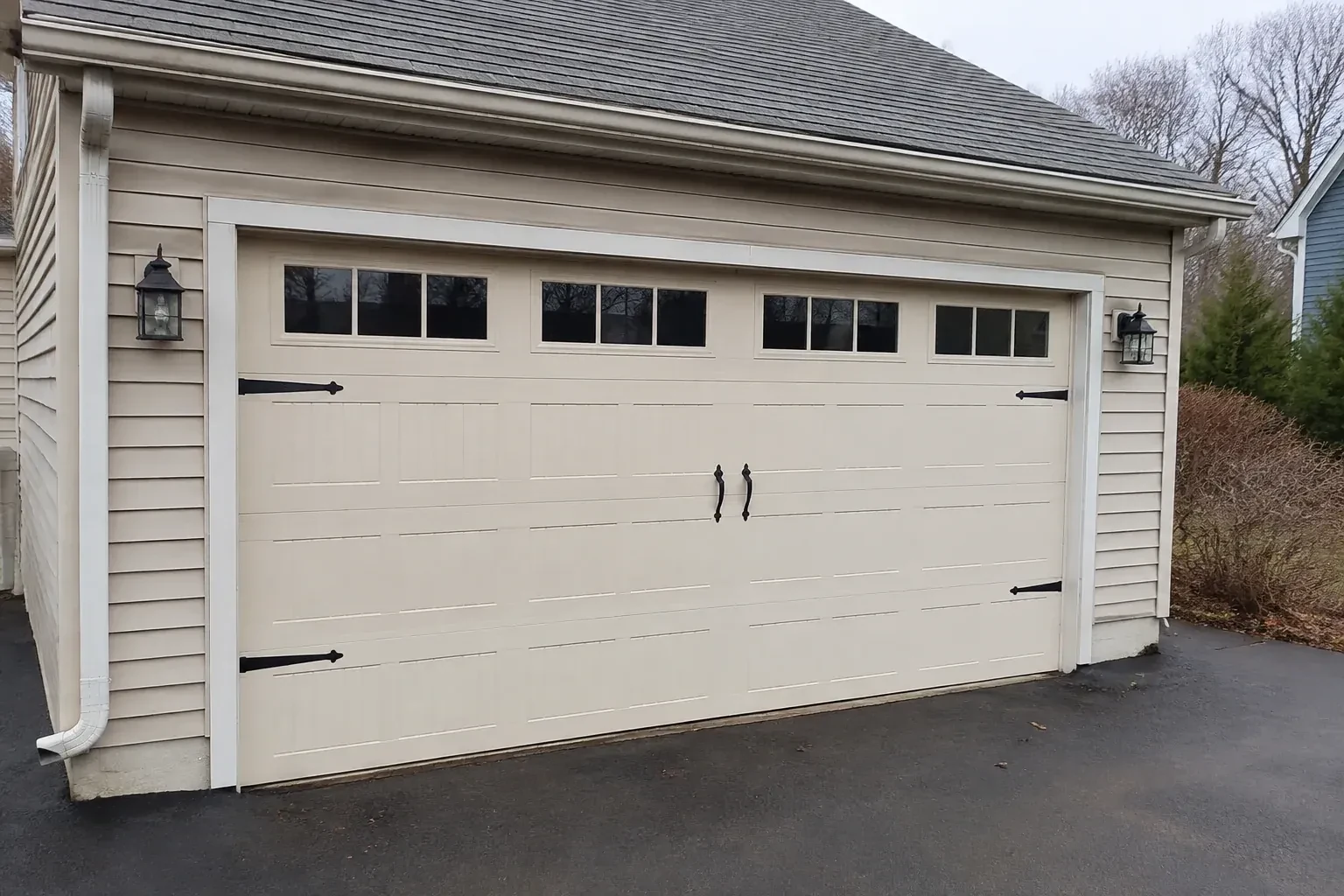 Cream carriage-house-style garage door with dark decorative hardware. — Carriage-House Garage Door Installation, Innisfil
