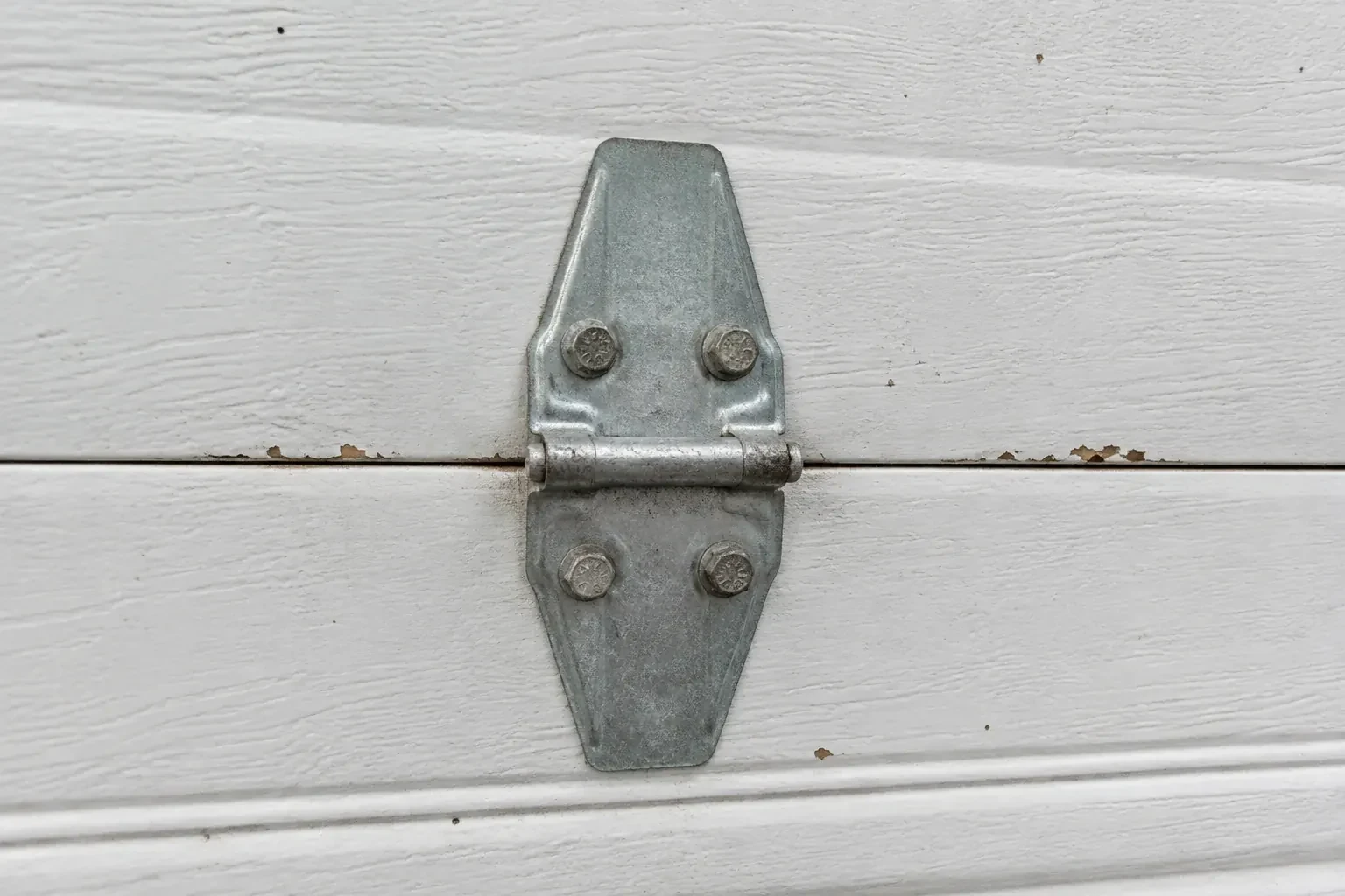 Metal center hinge across a seam in a white sectional garage door. — Garage Door Hinge Replacement, Innisfil